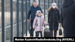 A woman and her daughter walk across the administrative border checkpoint at Stanytsya Luhanska, separating the separatist-controlled city of Luhansk from government-controlled territory in eastern Ukraine, on February 20