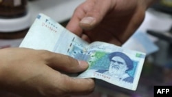 A woman pays with a 20,000-rial banknote in a grocery store in Tehran.