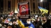 Demonstrators hold up signs and wave flags during a rally in support of Ukraine in Tbilisi on February 28.