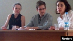 Former U.S. intelligence agency contractor Edward Snowden (center) and Sarah Harrison (left) of WikiLeaks speak to human rights representatives in Moscow's Sheremetyevo Airport on July 12.