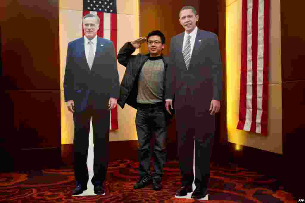 A man poses with carboard cutouts of U.S. President Barack Obama and presidential candidate Mitt Romney at a hotel during an event organised by the U.S. Embassy in Beijing.