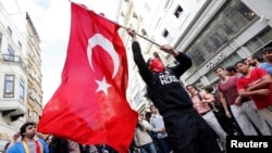 A masked demonstrator waves a Turkish flag during a protest in central Istanbul in late May.