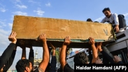 Iraqi mourners transport onto the roof of a vehicle the coffin of a person who was killed during clashes between anti-government protesters and security forces in the central holy Shi'ite shrine city of Najaf on November 28.