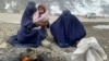 Gulnaz (left) keeps her 18-month-old son warm as they wait for alms along a highway in eastern Afghanistan.