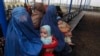 Afghan refugee women sit with their babies as they wait with others to be repatriated to Afghanistan at the UNHCR office on the outskirts of Peshawar in February.