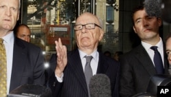 Media mogul Rupert Murdoch (center) talks to reporters after a July 15 meeting with the family of a murdered schoolgirl, Milly Dowler, whose phone had been hacked for "News of the World" reporting.