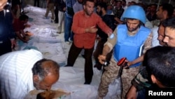 A UN observer takes pictures of the bodies of people whom antigovernment protesters say were killed by government security forces in Houla.