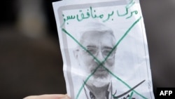 A pro-government supporter holds up a crossed-out portrait of Mir Hossein Musavi during a mass rally in Tehran last month.