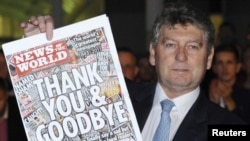 Colin Myler, editor of the "News of The World," holds up a copy of the last edition of the newspaper outside its office in Wapping, east London, on July 9.