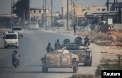 Hayat Tahrir al-Sham fighters drive along a street in Aleppo on November 29.