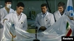 Iranian President Mahmud Ahmadinejad looks on next to scientists unveiling a fuel rod at the Tehran Research Reactor in February.