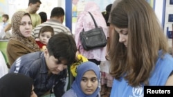 A UN worker takes down the names of Iraqi families at a refugee center in Damascus.