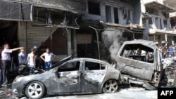 People look at burned-out car bombs after an attack that killed at least 10 people and wounded 62 in the Jaramanah suburb in southeast Damascus on July 25. 