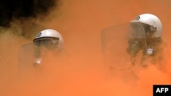 Greek riot policemen stand in smoke during clashes with demonstrators in front of the parliament in Athens on June 29.