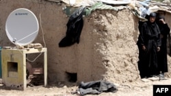 A TV satellite dish sits next next to a makeshift home in Baghdad's Al-Dora slum. (file photo)