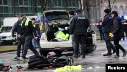 Police investigate the scene after an Afghan asylum seeker drove a car into a crowd in Munich, injuring 28 people. 