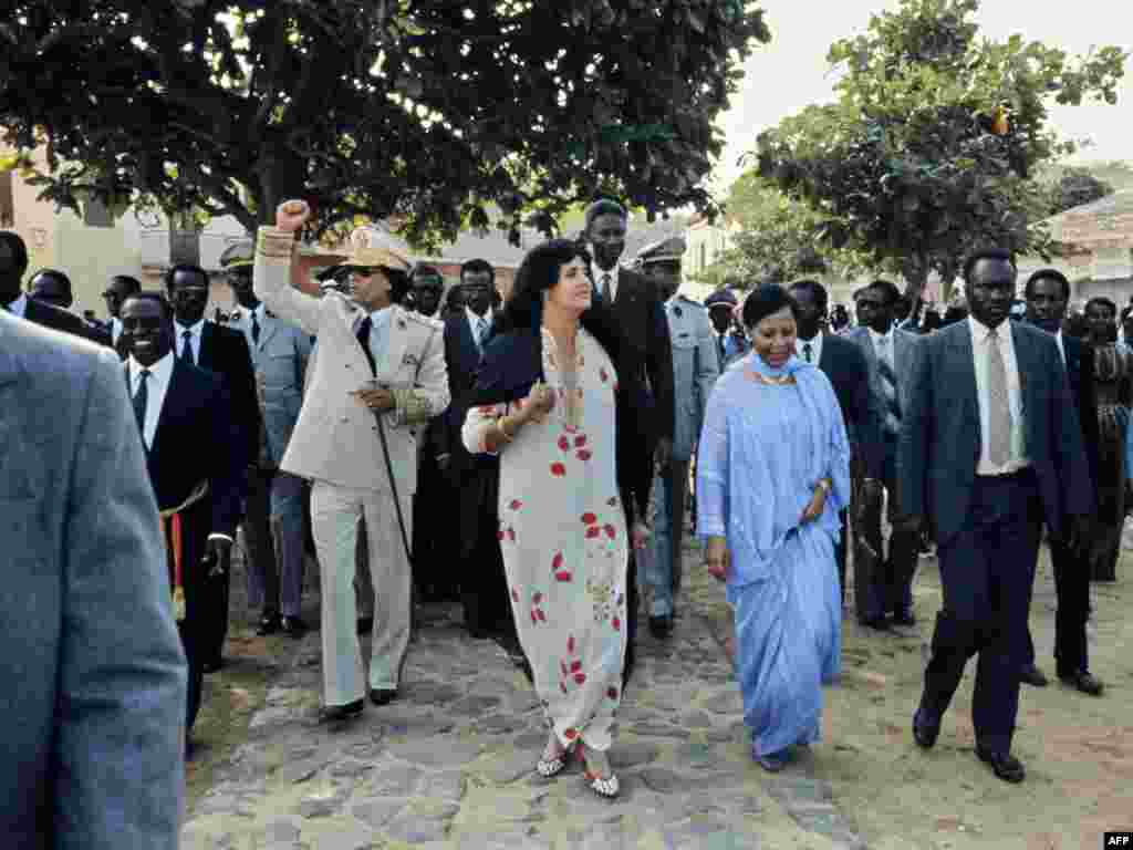 Qaddafi and his wife, Suffiya (in floral print dress), wave to the crowd upon their arrival for an official visit to Senegal in December 1985.