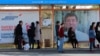 People wait for a bus in front of election campaign posters at a bus stop in the Kyrgyz capital, Bishkek. The country goes to the polls to elect a new president on October 15. 