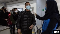 Passengers arriving at an airport in Iran are checked for the new coronavirus. 